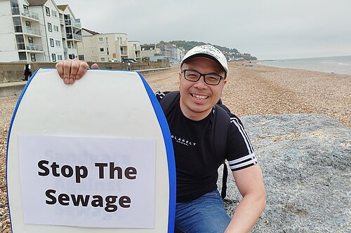 Larry Ngan with "Stop the Sewage" surfboard