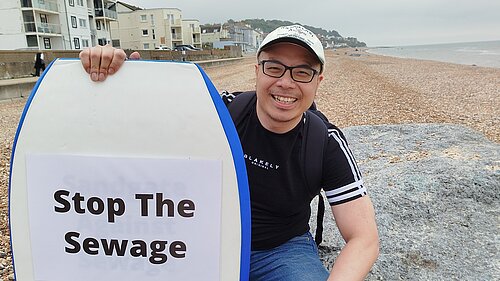 Larry Ngan with "Stop the Sewage" surfboard