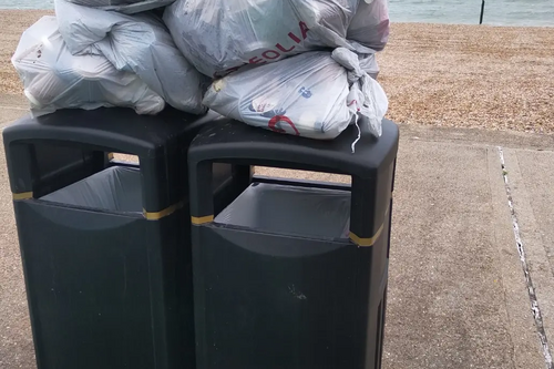 Rubbish bags piled on waste bins