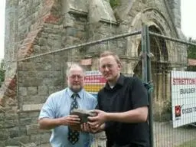 Neil Matthews and Gary Fuller at Christchurch Tower holding a stone