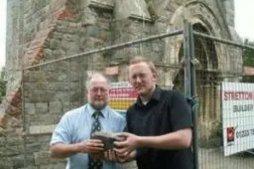 Neil Matthews and Gary Fuller at Christchurch Tower holding a stone